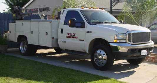 White Wells Tapping Service utility truck with a service body, parked on a driveway.